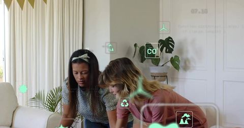 Two women collaborating over tablet with ar sustainability icons showing co2 and recycling