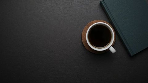 Minimalist workspace with coffee mug and book on dark surface