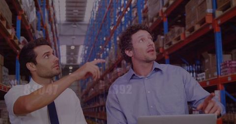 Warehouse Team Strategizing Amidst Industrial Shelving Units