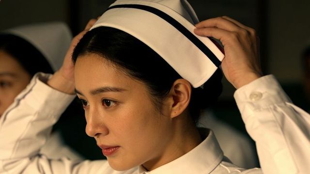 Nurse adjusting white cap in hospital ward conveying focused professionalism