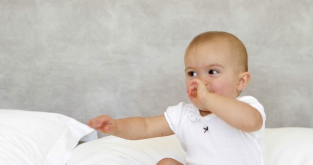 Cute Baby Sitting on Bed - Thumb Sucking and Smiling - Download Free Stock Images Pikwizard.com