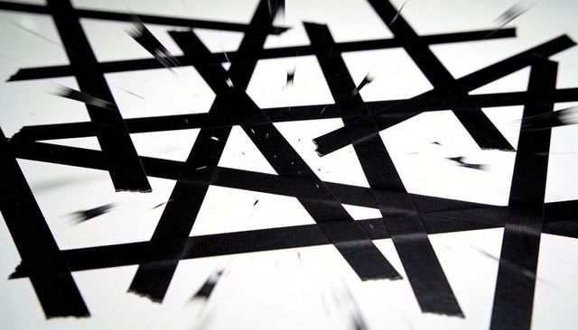 Abstract black tape lattice forming torn crisscross grid on white background motion blur