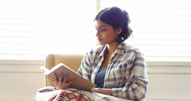 Young woman reading a book in cozy home setting - Download Free Stock Images Pikwizard.com