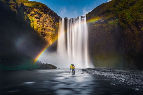 Photographer Capturing Rainbow at Majestic Waterfall with Silky Long Exposure and Scale