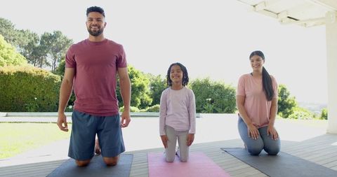 Family Kneeling On Yoga Mats During Outdoor Wellness Session