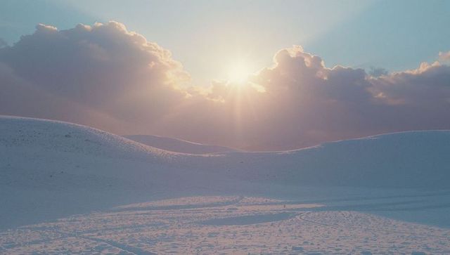 Golden Sunlight over Snow-Covered Desert Landscape with Clouds