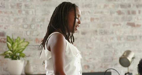African american woman speaking in minimalist home studio with exposed brick and lamp