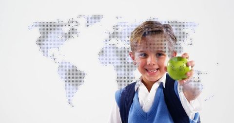 Smiling schoolboy holding green apple suggesting global learning and healthy habits