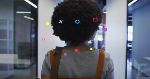 Rear view woman walking through modern office with augmented reality geometric overlays