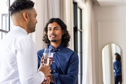 African american men holding drinks and talking by window casual workplace conversation
