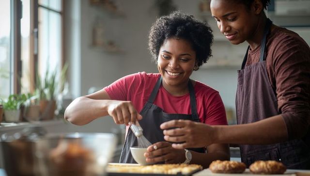 Smiling couple baking together in bright kitchen, whisking batter and arranging pastries