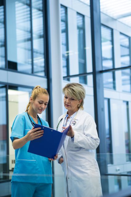 Female doctor and nurse reviewing a medical report in a modern hospital setting. Ideal for use in healthcare-related articles, medical websites, hospital brochures, and educational materials showcasing professional collaboration and patient care.