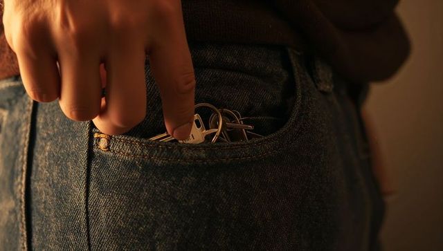 Hand reaching into denim pocket retrieving keys with white tag