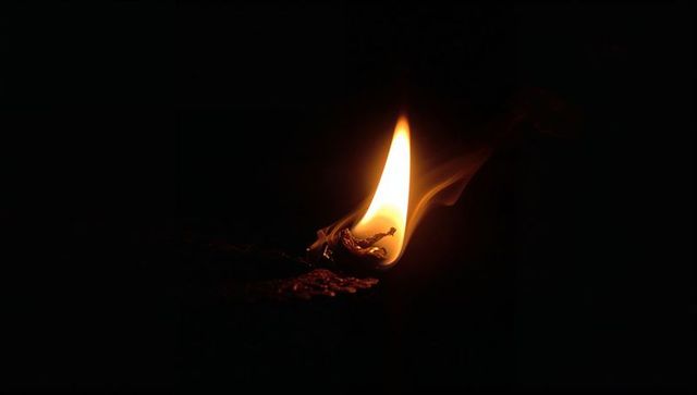 Burning matchstick illuminating dark backdrop with intense flame