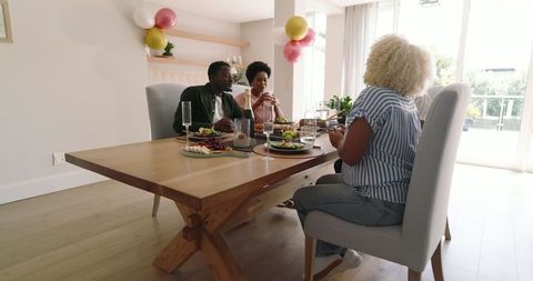 Friends Sharing Laughter Over Lunch in Bright Modern Dining Room