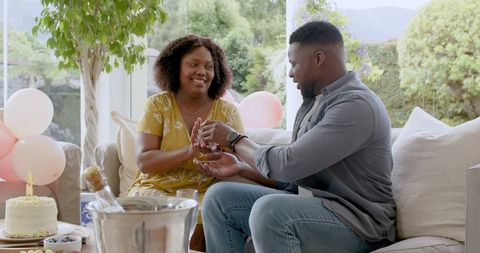 Couple Celebrating Birthday at Home with Cake and Champagne