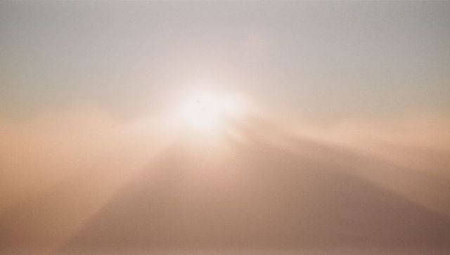 Bright Sun Rising Over Misty Mountain Ridge Silhouette at Dawn