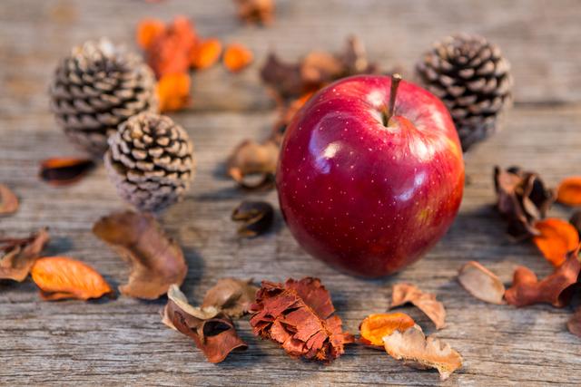 Red Apple and Pine Cones on Rustic Wooden Plank - Download Free Stock Photos Pikwizard.com