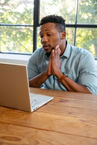 Thoughtful Professional Engaging with Laptop in Bright Office