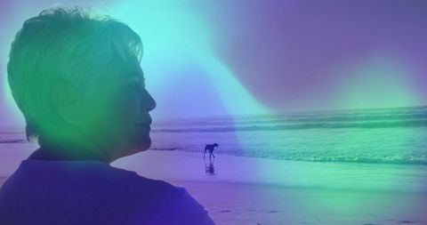 Senior woman reflecting at beach with gentle waves and distant dog