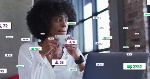 Professional woman sipping coffee while receiving social media notifications at laptop