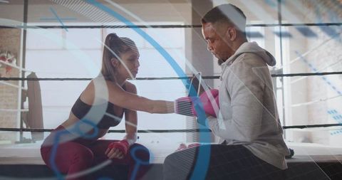 Female boxer training with coach holding pink mitts in industrial daylight boxing ring