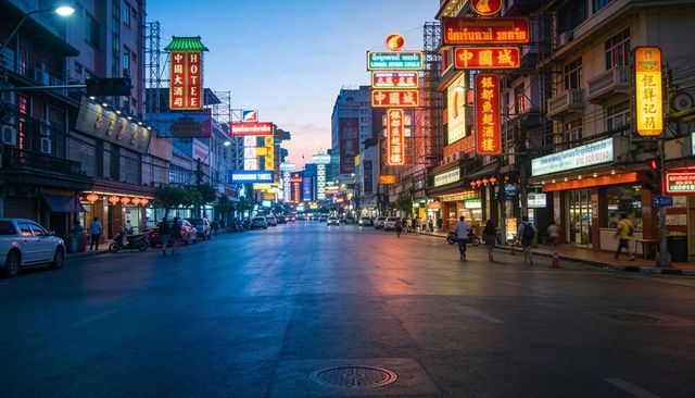 Neon chinatown street at dusk reflecting on wet road with glowing chinese and thai signs