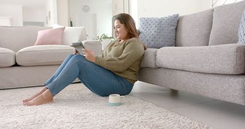 Smiling Woman Relaxing with Tablet in Cozy Living Room