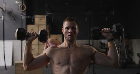 Focused Man Lifting Dumbbells in Urban Gym