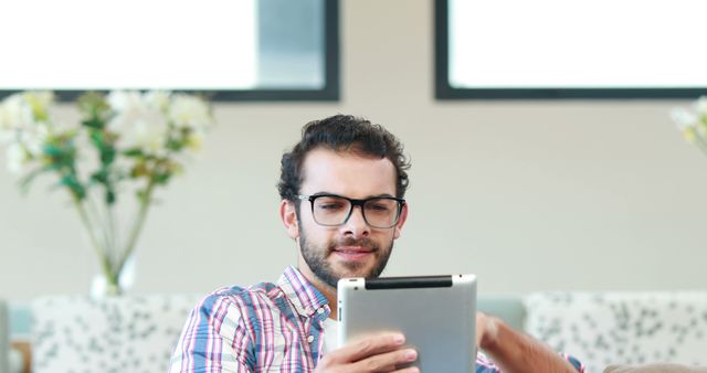 Young Man with Glasses Using Tablet at Home - Download Free Stock Images Pikwizard.com