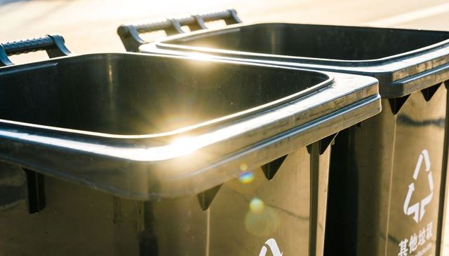 Sunlight catching urban recycling bins showing chinese characters and lens flare