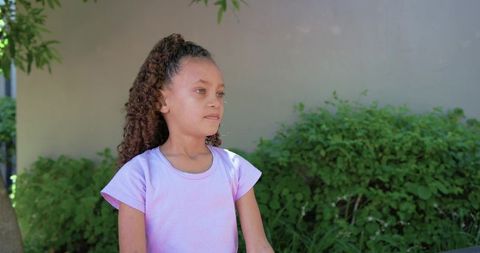 Contemplative african american girl standing outdoors wearing light purple t-shirt