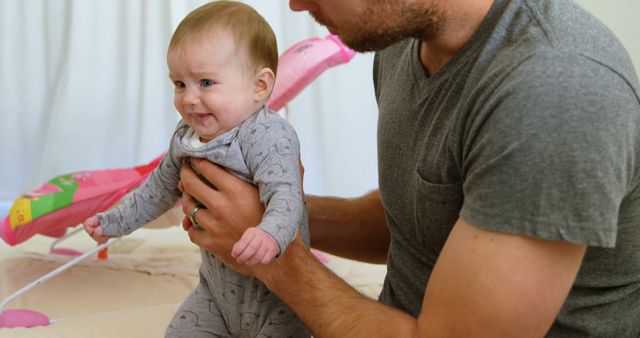 Father holding smiling baby in nursery room - Download Free Stock Images Pikwizard.com