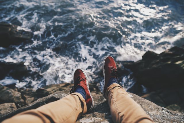 Person Relaxing on Cliff with Shoes Dangling Over Ocean - Download Free Stock Photos Pikwizard.com