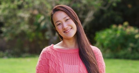 Joyful Asian Woman Smiling Outdoors in Cozy Sweater