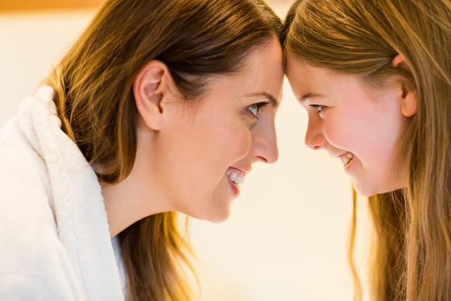 This image captures a joyful moment between a mother and her daughter as they look at each other with affection. Ideal for use in family-oriented advertisements, parenting blogs, and articles about family relationships and home life.