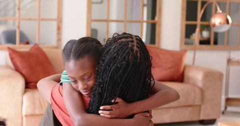 African american mother and daughter sharing warm hug on cozy beige sofa
