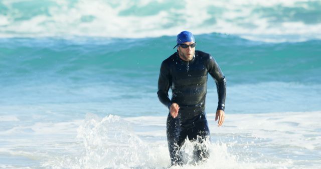 Male Swimmer Emerging from Waves at Beach Wearing Wetsuit and Swimming Cap - Download Free Stock Images Pikwizard.com