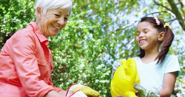 Older woman and young girl enjoy gardening together in a lush, green outdoor space. Perfect for illustrating themes of family bonding, nature activities, and multigenerational relationships. Ideal for articles or advertisements promoting outdoor activities, family time, and teamwork.