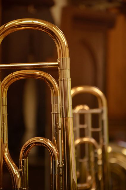 This image shows a close-up view of shiny brass trombones, ideal for use in contexts involving music, symphonies, orchestras, or bands. It can be used for promotional material for musical events, educational content about brass instruments, or decoration where music and instruments are the focus.