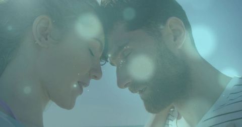Intimate couple leaning foreheads together in dreamy teal light with bokeh