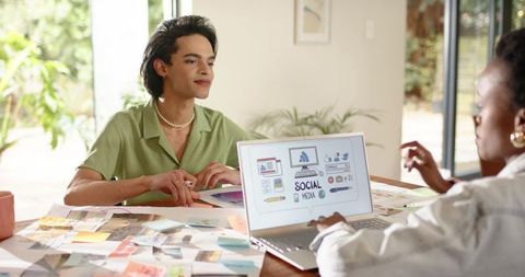 Collaborating on social media mockups in bright home workspace with laptop and moodboards