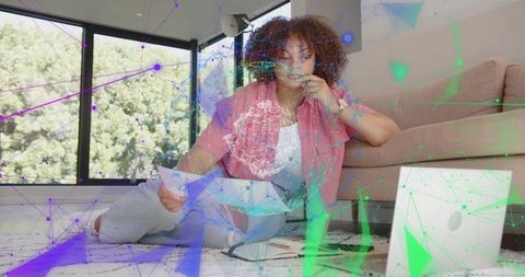Remote professional reviewing papers in living room with laptop and network visualization