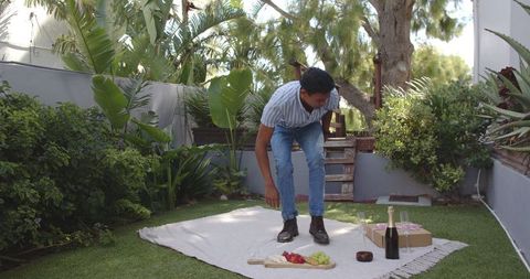 Man preparing relaxing picnic in lush backyard garden