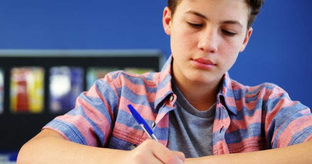 Teen Boy Concentrating On Writing In Classroom - Download Free Stock Images Pikwizard.com