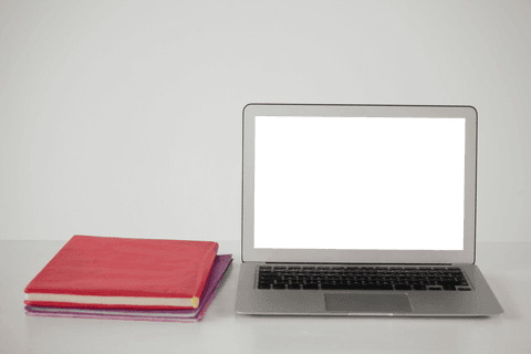 Transparent laptop display with books on desk