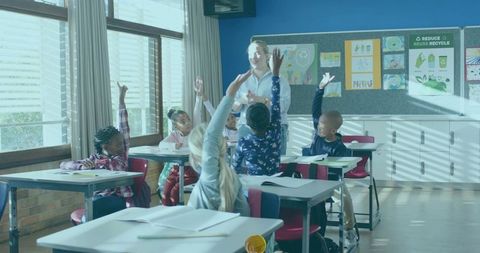 Elementary students raising hands during interactive classroom lesson with teacher
