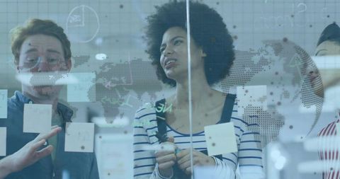 Diverse team brainstorming on glass with sticky notes and dotted world map overlay