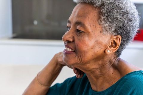 Senior african american woman resting chin on hand, contemplative and serene home portrait