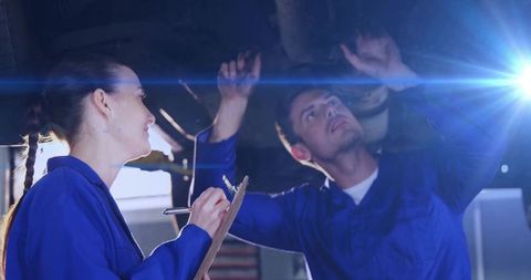 Two mechanics inspect vehicle undercarriage on lift